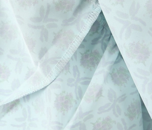 Detailed macro shot of blue floral fabric showing high-quality overlock stitching