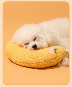U-shaped yellow plush cat pillow with floral embroidery used by a sleeping pet