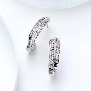 Detailed view of silver cross-curved stud earrings with pavé cubic zirconia on white silk