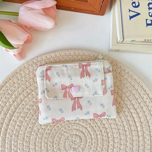 Detailed view of floral canvas card wallet on a woven mat with heart-shaped buckle