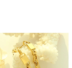 Macro detail of gold geometric choker chain draped over white coral background