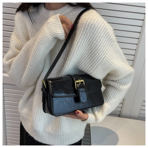 Detail of vintage black leather bag with glossy texture and large gold buckle closure