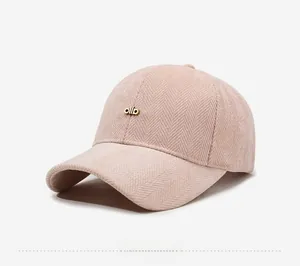 Detail of pink herringbone texture baseball cap with golden metal logo accent