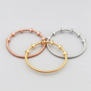 Detailed shot of three nut-style metal bracelets in rose gold, gold, and silver finishes