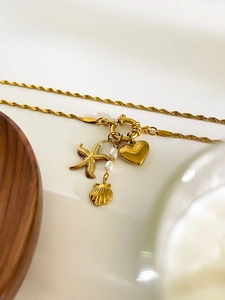 Detailed shot of gold titanium necklace featuring starfish, heart, and pearl charms