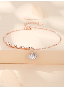 Detail of rose gold ginkgo leaf bracelet with sparkling cubic zirconia on warm background