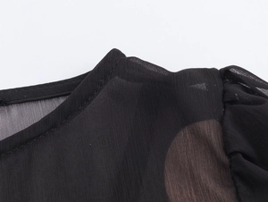 Détail de la couture de l'encolure sur une robe en mousseline noire au tissu semi-transparent