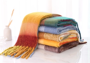 Detail of colorful plaid scarf stack with fringe on marble table under soft light