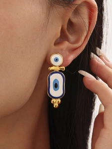 Close-up of dangling gold evil eye earrings with blue enamel on a female model