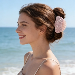 Detail of seashell hair claw with gradient pink pearlescent finish in outdoor beach setting