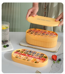 Double-layer orange ice cube tray with fruit-filled cubes on marble tray