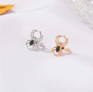 Close-up of spider-shaped jewelry in gold and silver finish with black gemstone detail