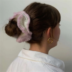 Detail of ruffled knitted scrunchie in cream and pink shown on hair bun stylishly