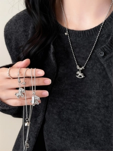 Gros plan du pendentif cheval à bascule en argent avec zircons et breloque Good Luck