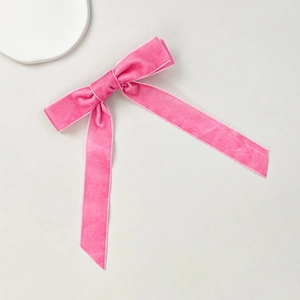 Detailed view of pink velvet bow hair clip with white piped edges on elegant display