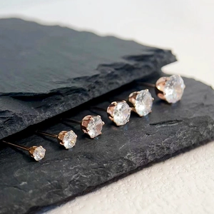 Detailed view of six pairs of rose gold sparkling zircon stud earrings on black rock