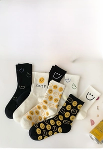 Close-up of cotton crew socks featuring knitted yellow smiley face pattern and Smile text