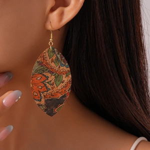 Close-up of bohemian leaf-shaped leather earrings with vintage ethnic floral patterns