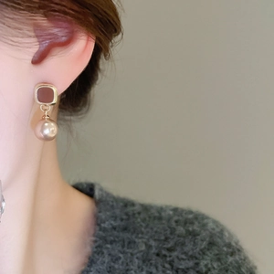 Detail of vintage square gold stud earring with round champagne faux pearl on model