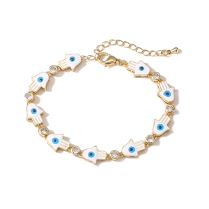 Detailed macro view of gold Hamsa Hand bracelet with blue evil eye enamel and cubic zirconia