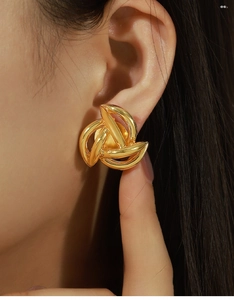 Close-up of a model wearing gold irregular geometric knot earrings in minimalist design