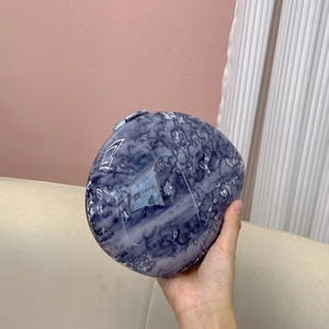 Detailed view of the marble pattern evening clutch bag held by a person for size display