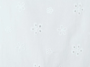 Close-up of white floral broderie anglaise embroidery on textured cotton fabric