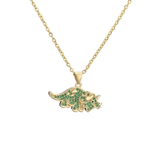 Detailed close-up of golden triceratops pendant with sparkling green zircon crystals