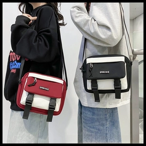 Detail of color-block canvas crossbody bags with dual buckle closure and woven label