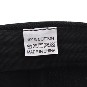 Detail showing white wash care label on black 100% cotton fabric baseball cap