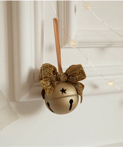 Close-up of matte gold metal bell with glitter bow and star cutout for Christmas decor