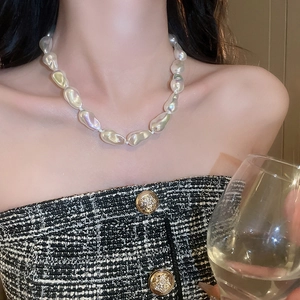 Macro detail of irregular Baroque pearl necklace worn with elegant black tweed outfit
