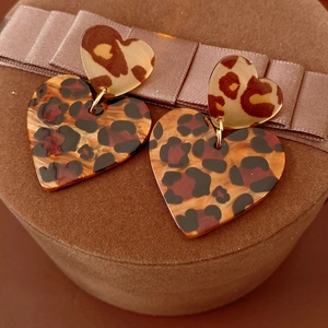 Close-up of leopard print heart earrings on a brown velvet box with ribbon