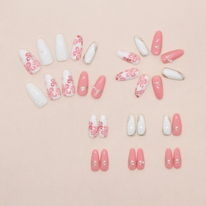 Detail of pink and white press-on nails with 3D pearl flowers and golden floral patterns