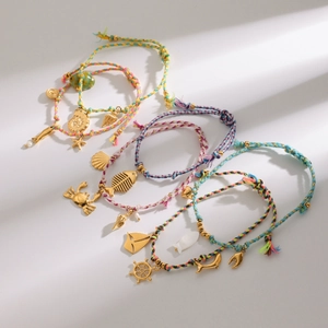 Detailed view of ocean-themed braided rope bracelets with various gold metal charms