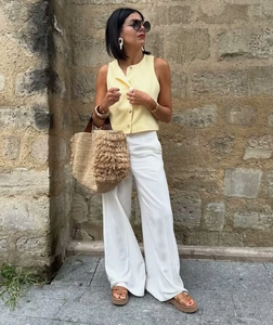 Outdoor shot of sleeveless yellow cotton linen vest paired with white wide-leg trousers
