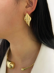 Close-up of elegant gold wavy earrings and matching choker necklace on a female model