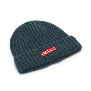 Détail du bonnet en maille bleu marine avec écusson brodé Hello rouge sur le revers