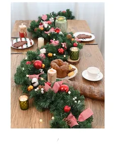 Detailed Christmas garland with red bows and pine cones on a rustic wooden dining table