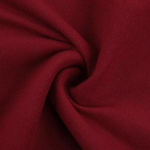 Dettaglio macro del tessuto rosso vino con morbide pieghe a spirale sull'abito aderente