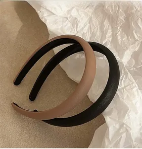 Close-up of khaki and black leather headbands with fine lychee texture on soft background