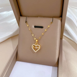 Close-up of gold heart pendant with crystal inlays on a beige velvet jewelry display