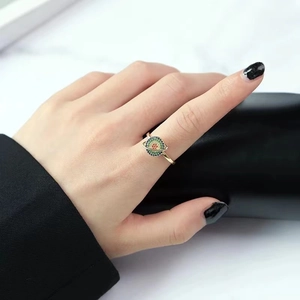 Macro shot of gold Saturn ring with colorful gems worn on a finger with black nails