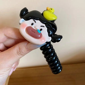 Close-up detail of cute cartoon girl charm with little yellow duck on black telephone wire hair tie.