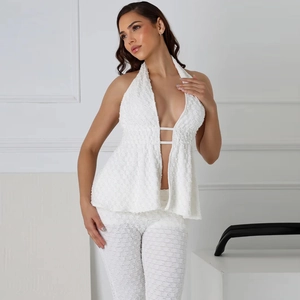 Detail of white halter neck top and high-waist pants with textured lace fabric
