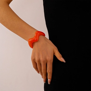 Detail showing wavy orange acrylic resin bangle with a translucent finish on wrist
