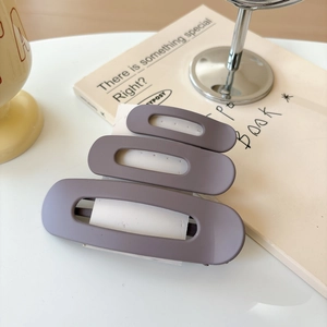 Detail view of three purple matte oval duckbill hair clips on white display card