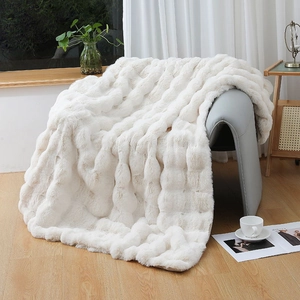 Close-up of fluffy white faux rabbit fur blanket with luxury 3D grid texture on gray chair