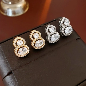 Detail of gold and silver plated gourd stud earrings with zircons on leather pad