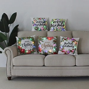 Detail showing five Christmas pillows with LED lights and Merry Christmas wreath patterns